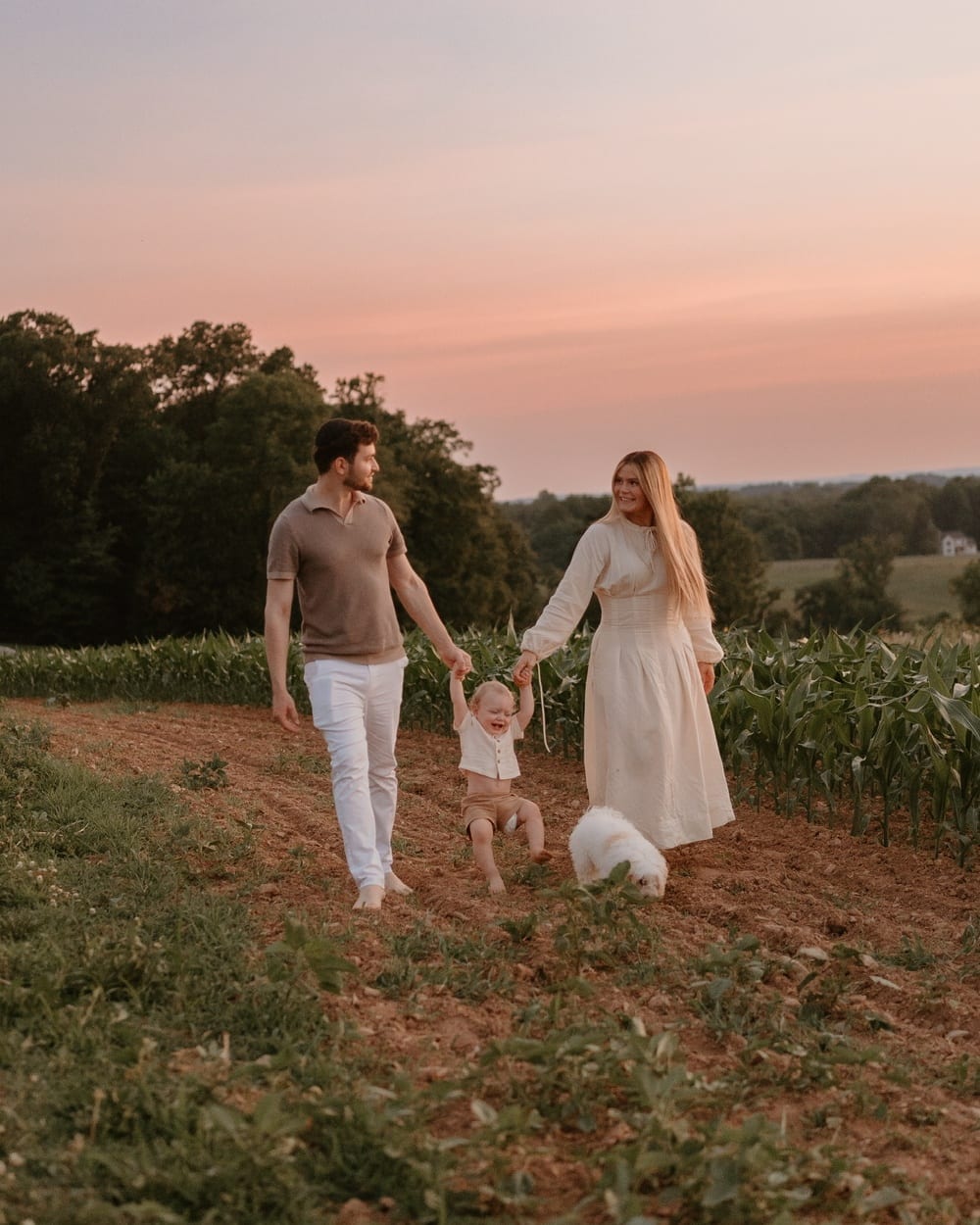 Yaacov, his wife Ethel and their baby Shalom walking through a farm field at sunset, Shalom swinging between them and Molly the dog trotting alongside